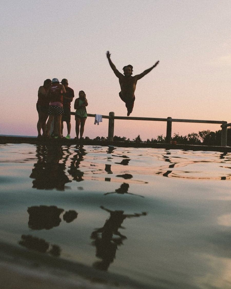 Friends jumping into a lake at sunset