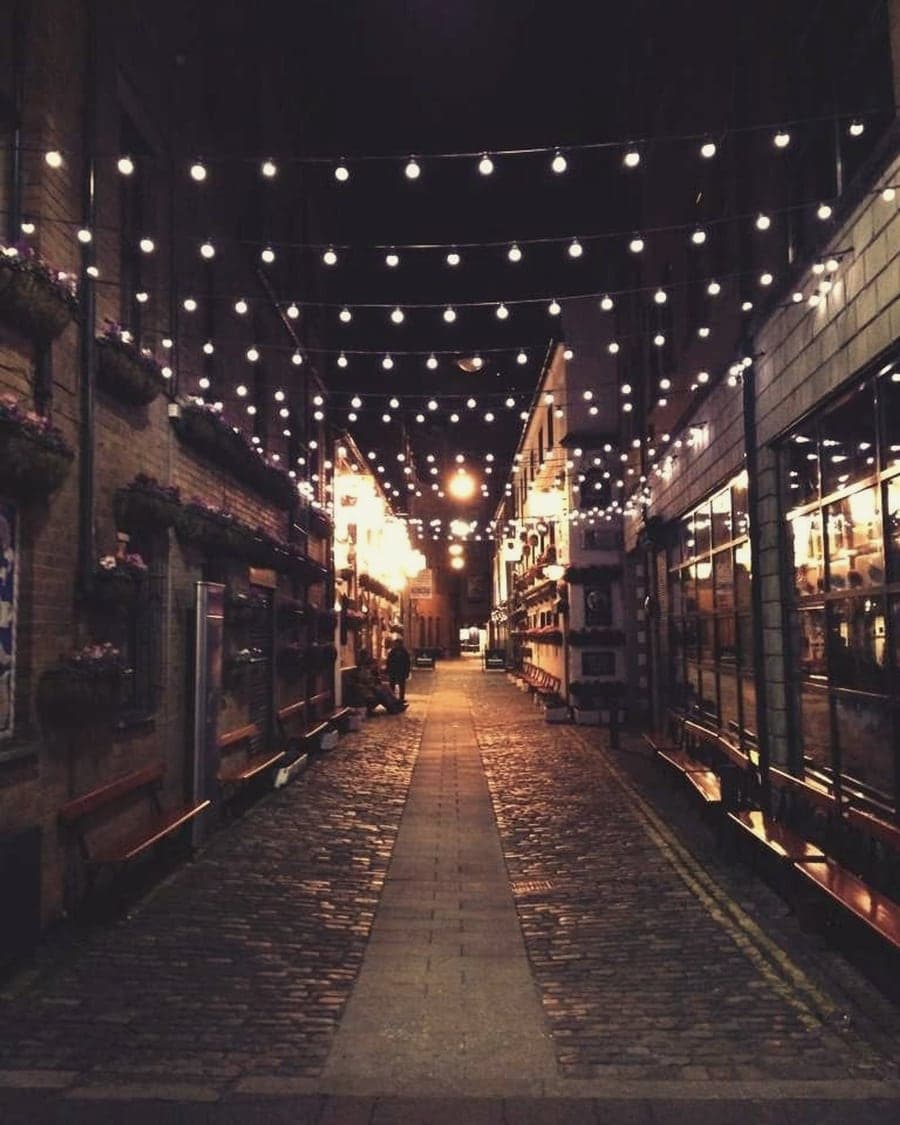 A street lit with string lights at night